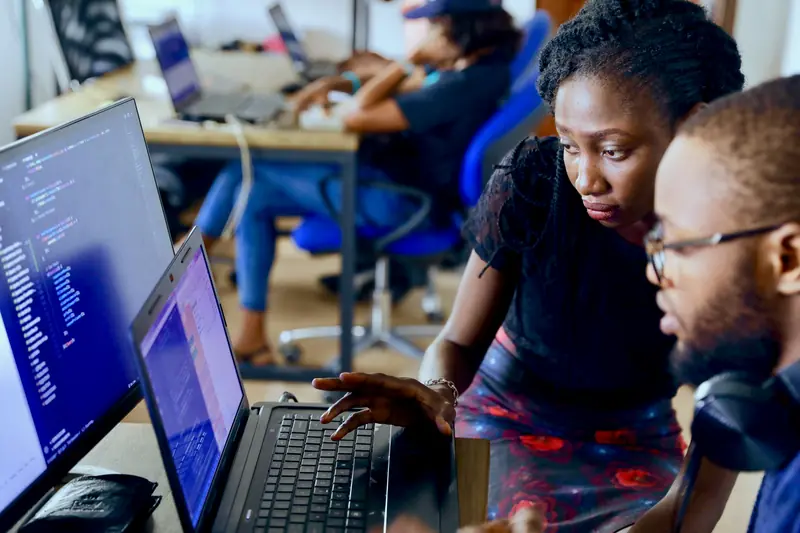 A team working together at laptops and monitors in a technology workspace
