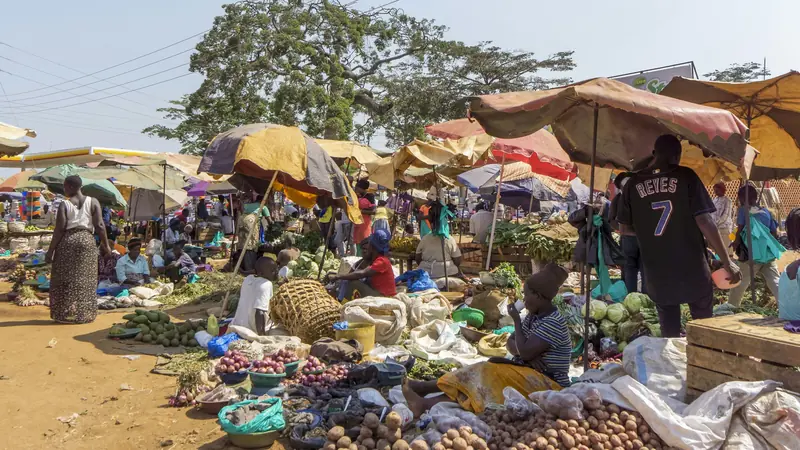 Busy open-air market in Entebbe, Uganda, with traders under shade umbrellas