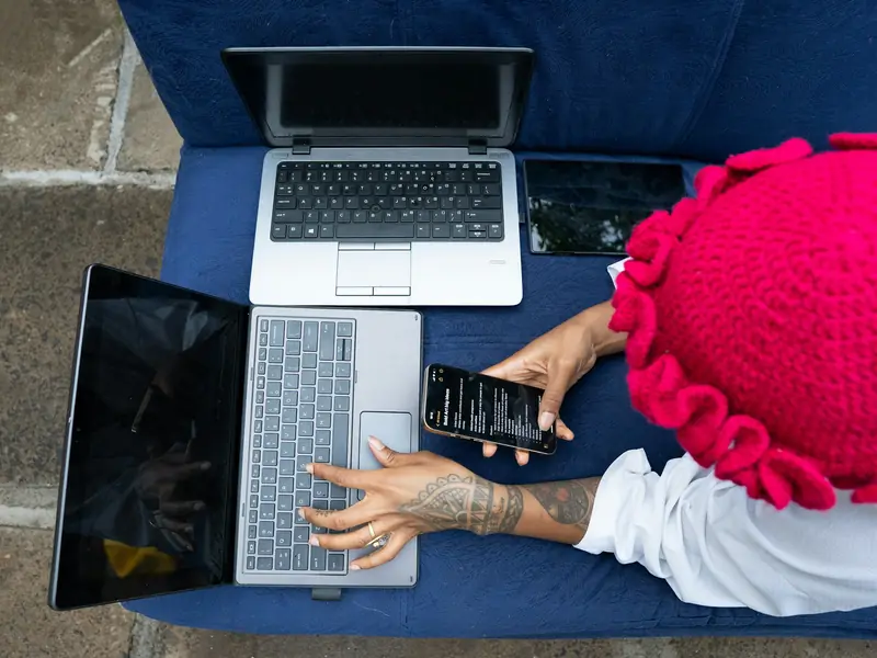 Working across two laptops and a phone in Nairobi, Kenya